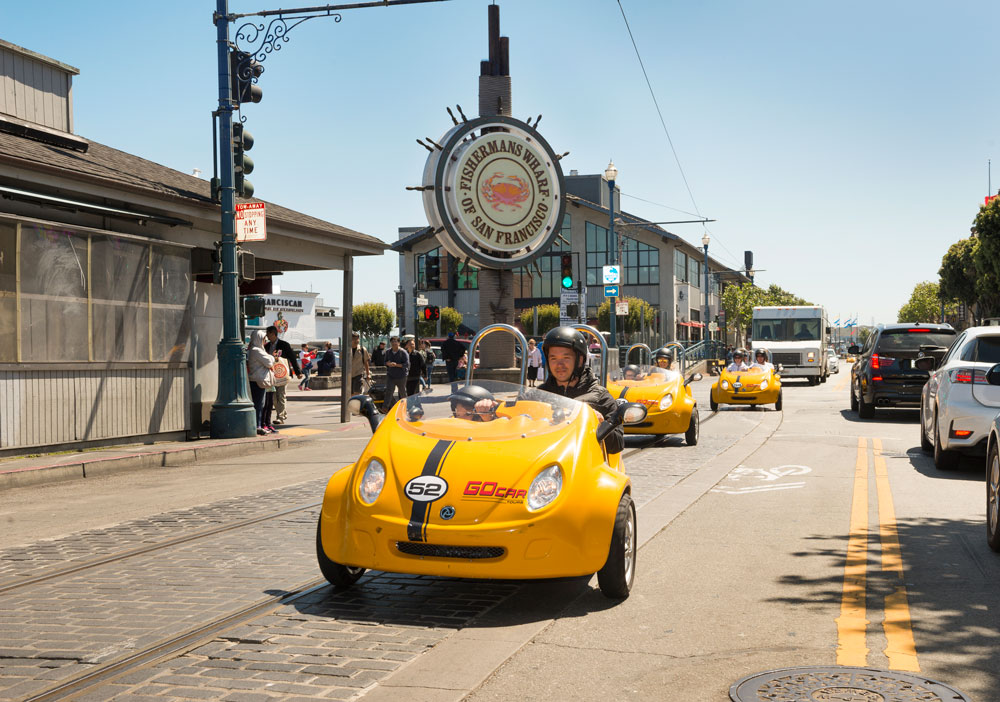 Family Driving GoCars Past the Fishermans Wharf Sign in San Francisco