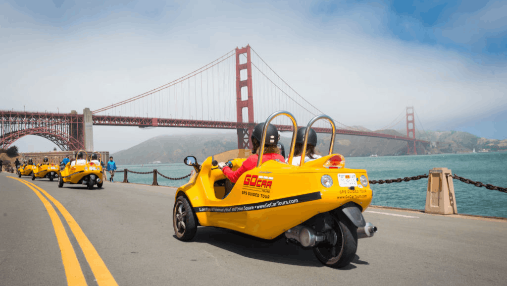 warm beaches in san francisco a yellow gocar driving along the water in san francisco