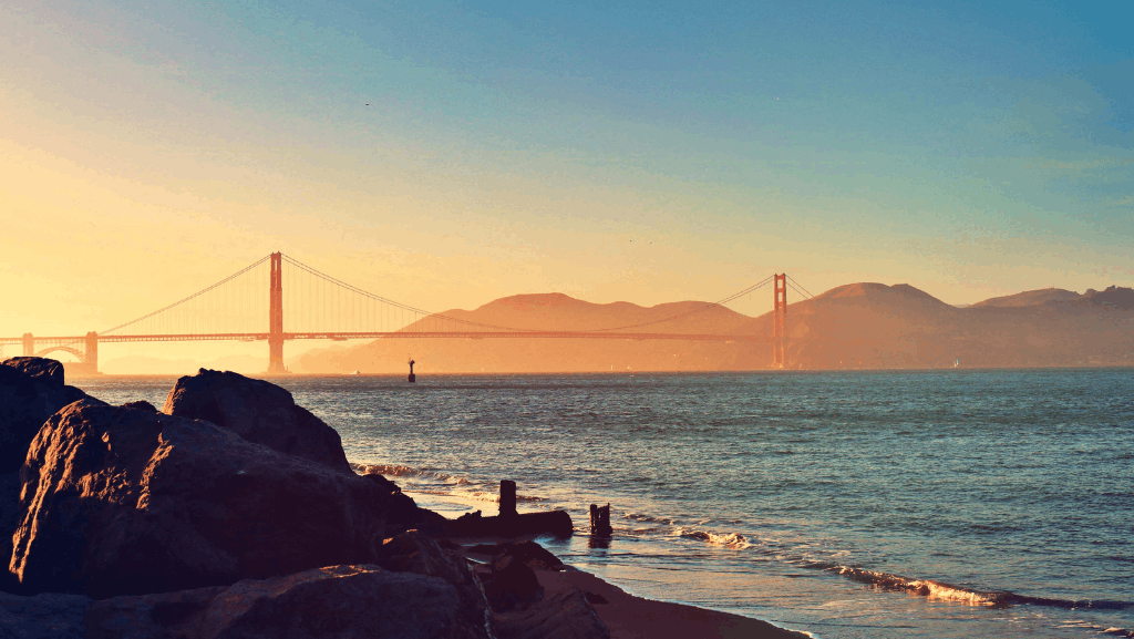 sunset over the golden gate bridge from a warm beach near san francisco